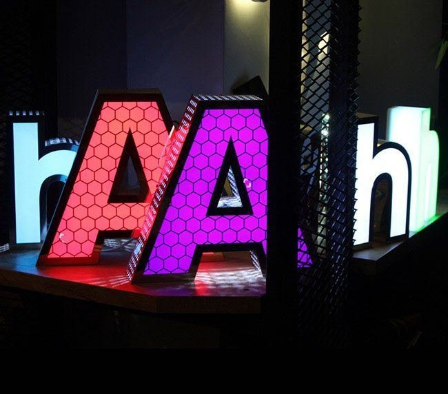 Illuminated channel letters glowing red, purple and white