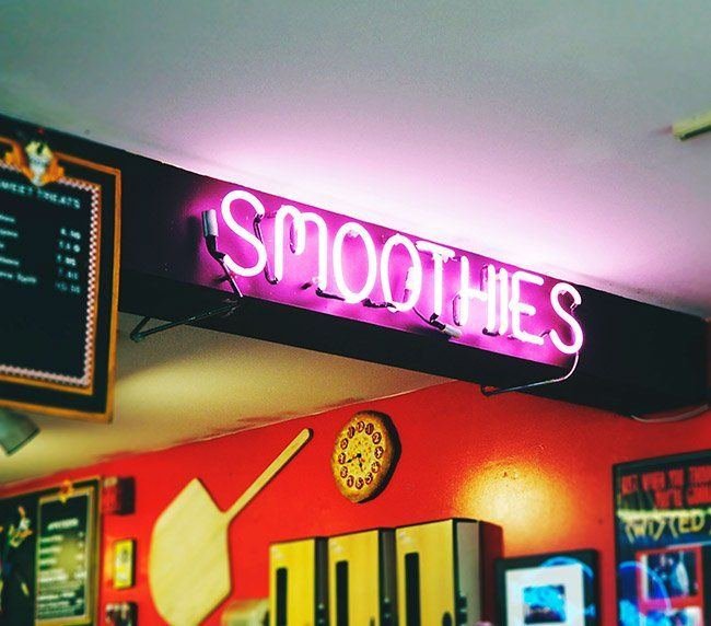 Pink neon Smoothies sign above a juice bar counter
