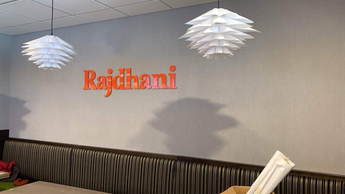 Orange dimensional Rajdhani logo on a restaurant dining room wall